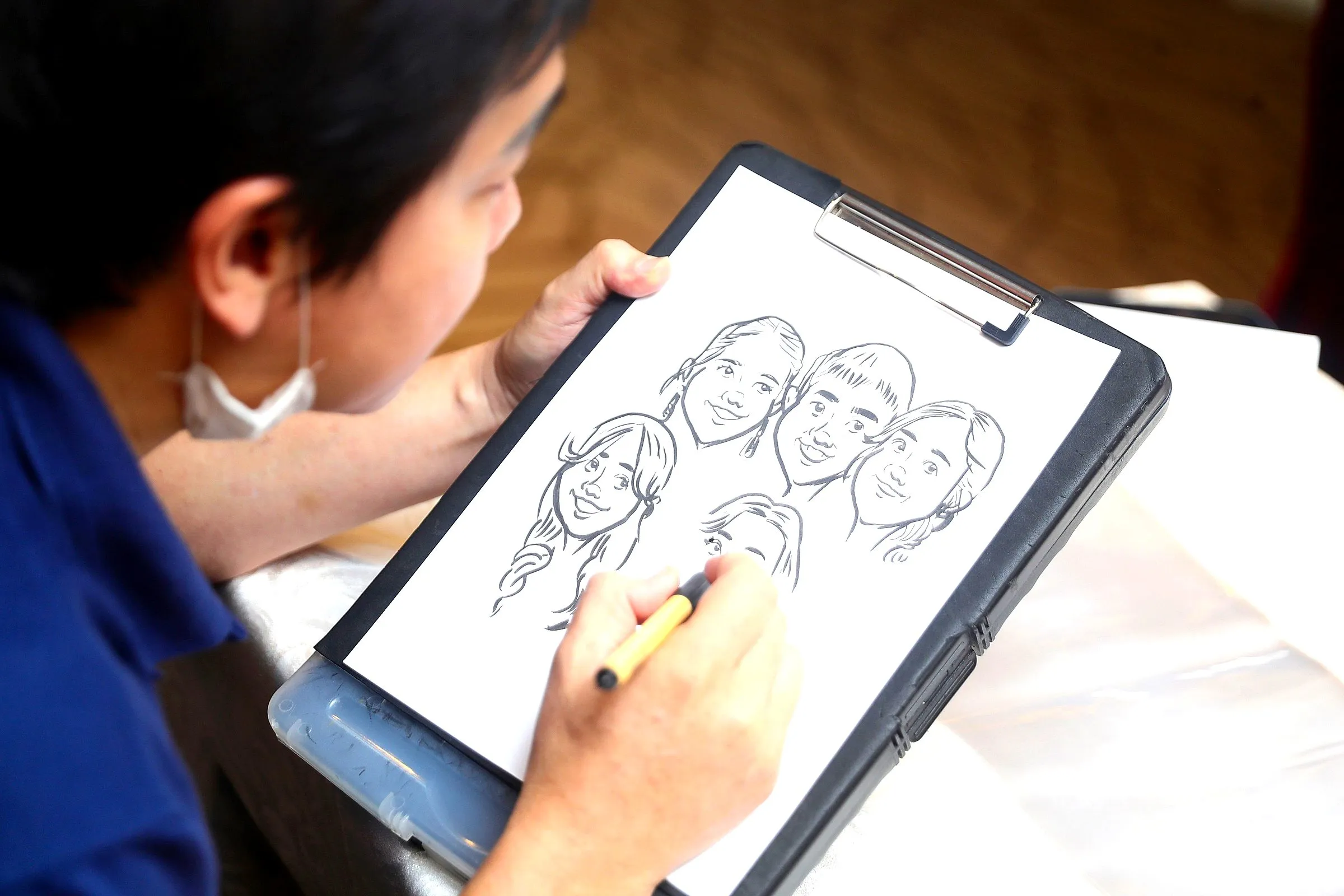 Caricature artist drawing a group portrait on a tablet