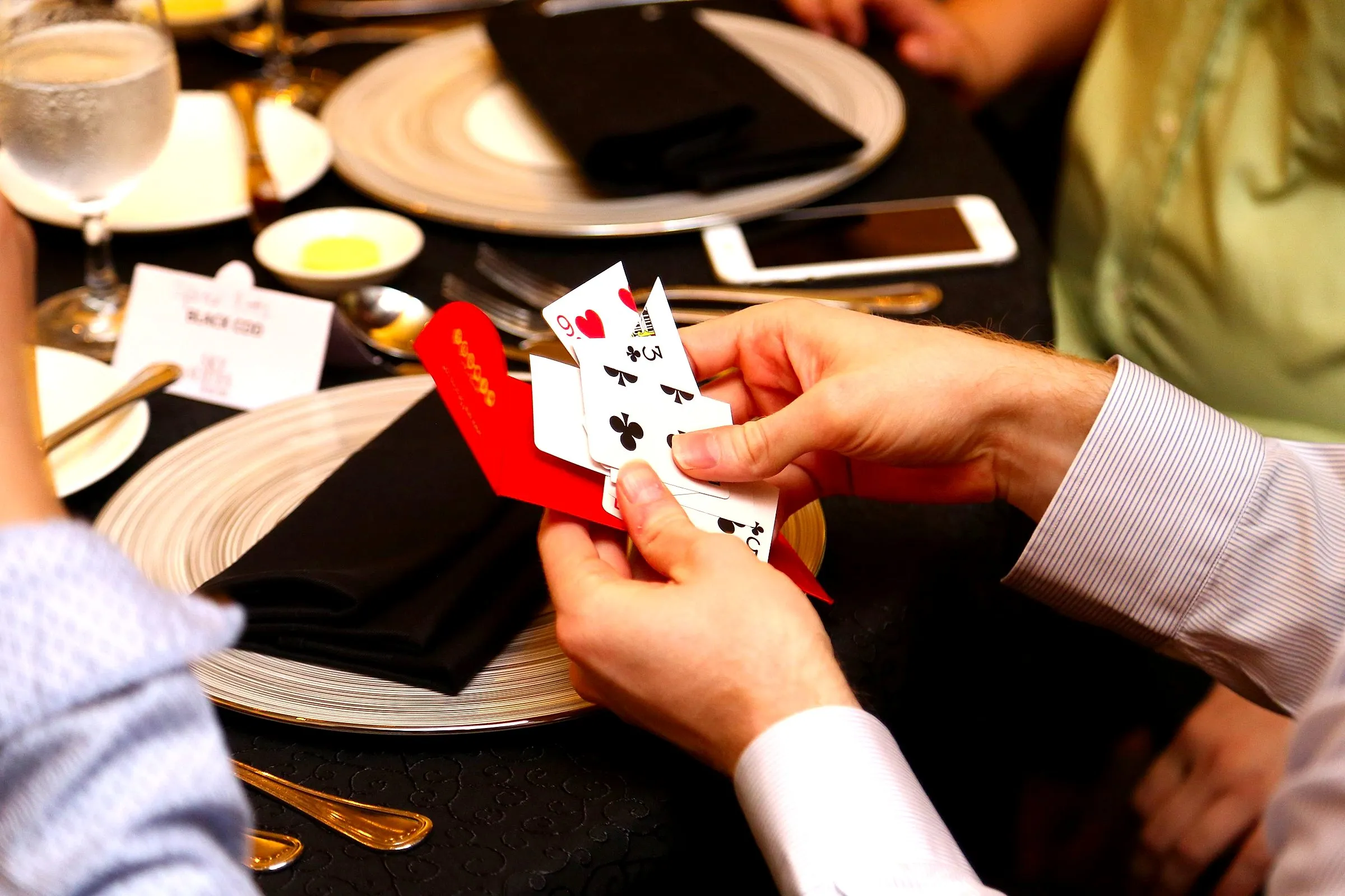 Close-up of a card trick performed over a dinner table